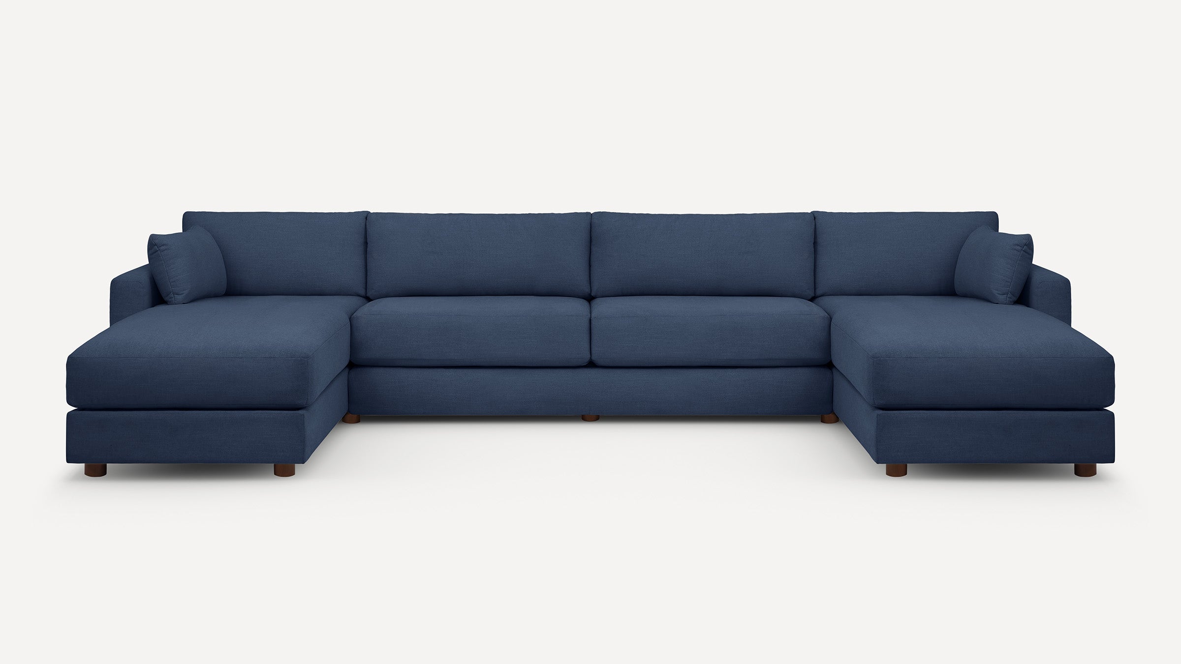 Large modern navy blue sectional sofa with clean lines, plush cushions, and wooden legs, featuring chaise lounges on both ends.