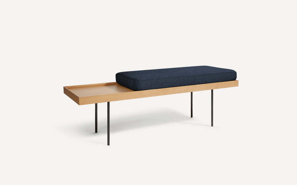 modern wooden bench with blue cushion and black metal legs on white background