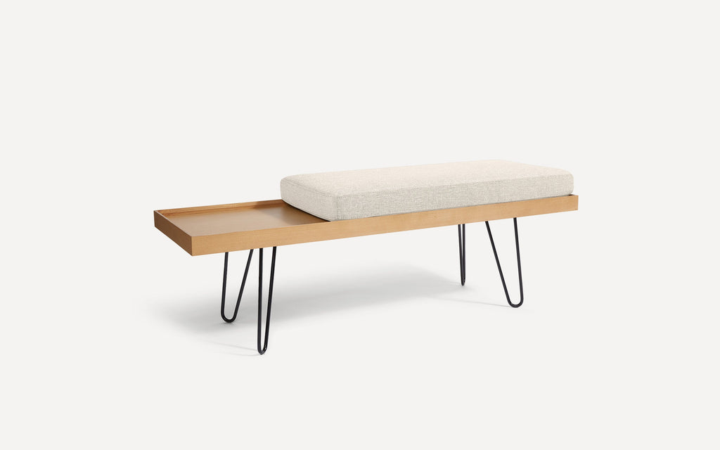 modern wooden bench with a beige upholstered cushion and black hairpinned legs on a white background
