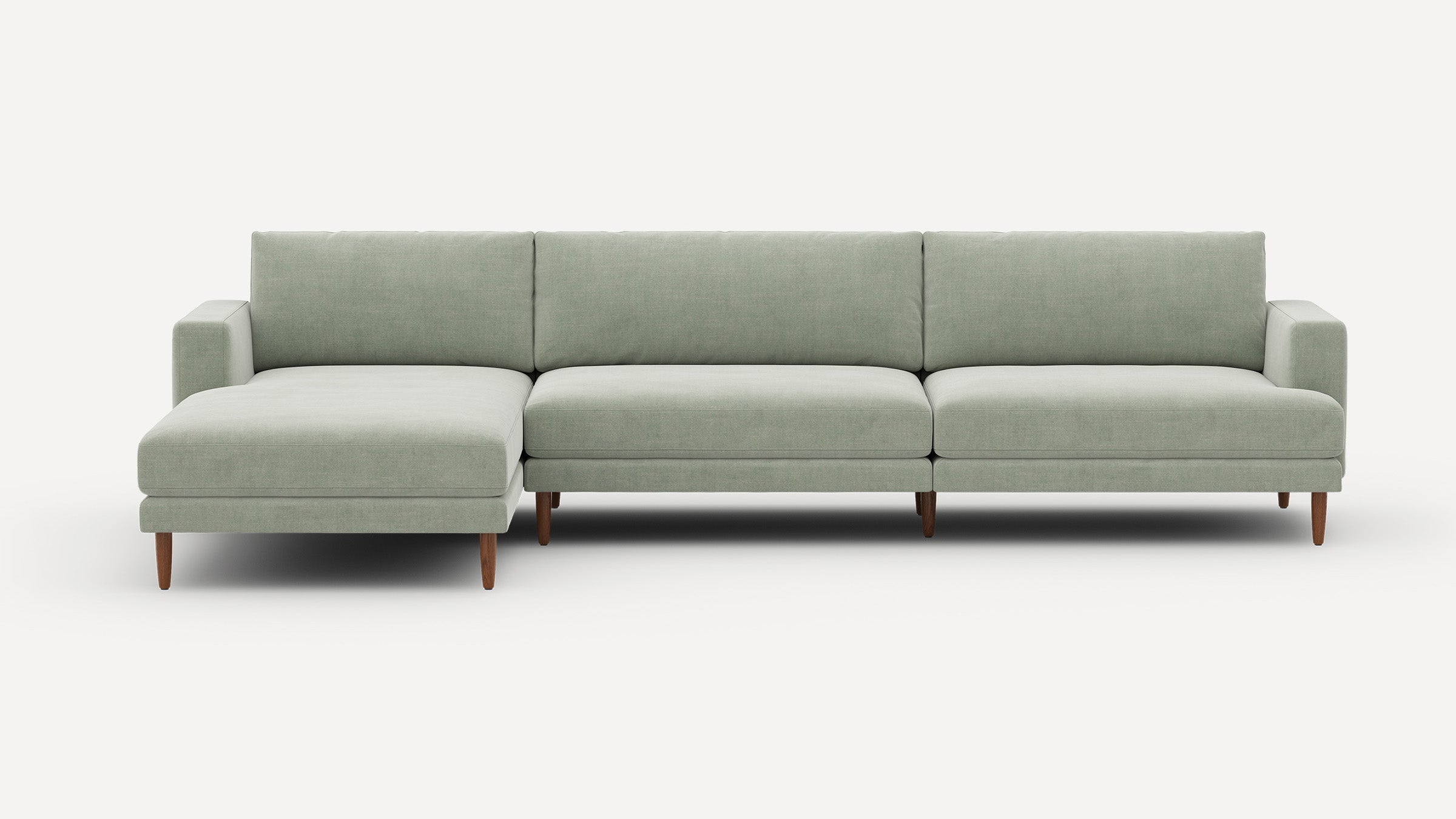 Light green fabric sectional sofa with wooden legs, featuring a left chaise and three seat cushions.