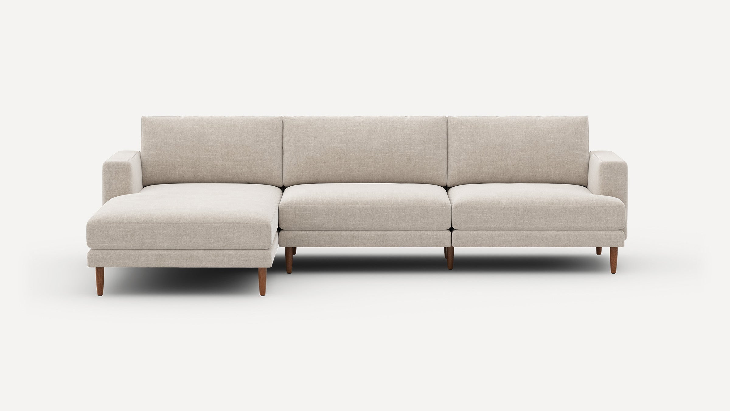 Modern beige sectional sofa with chaise lounge on left, wooden tapered legs, and clean lines against white background.