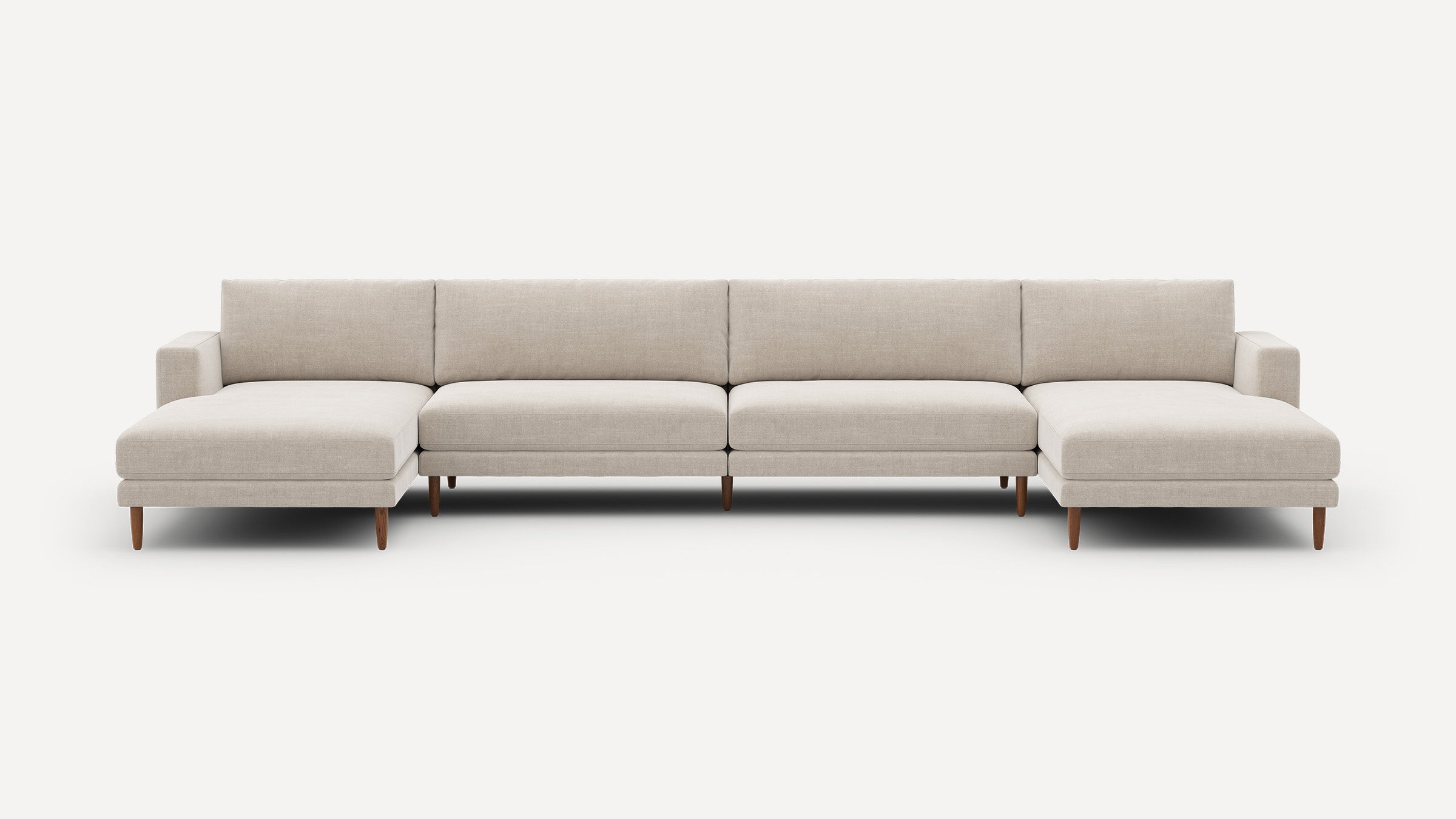 Large modern beige sectional sofa with clean lines, wooden legs, and chaise lounges on both ends against a white background.