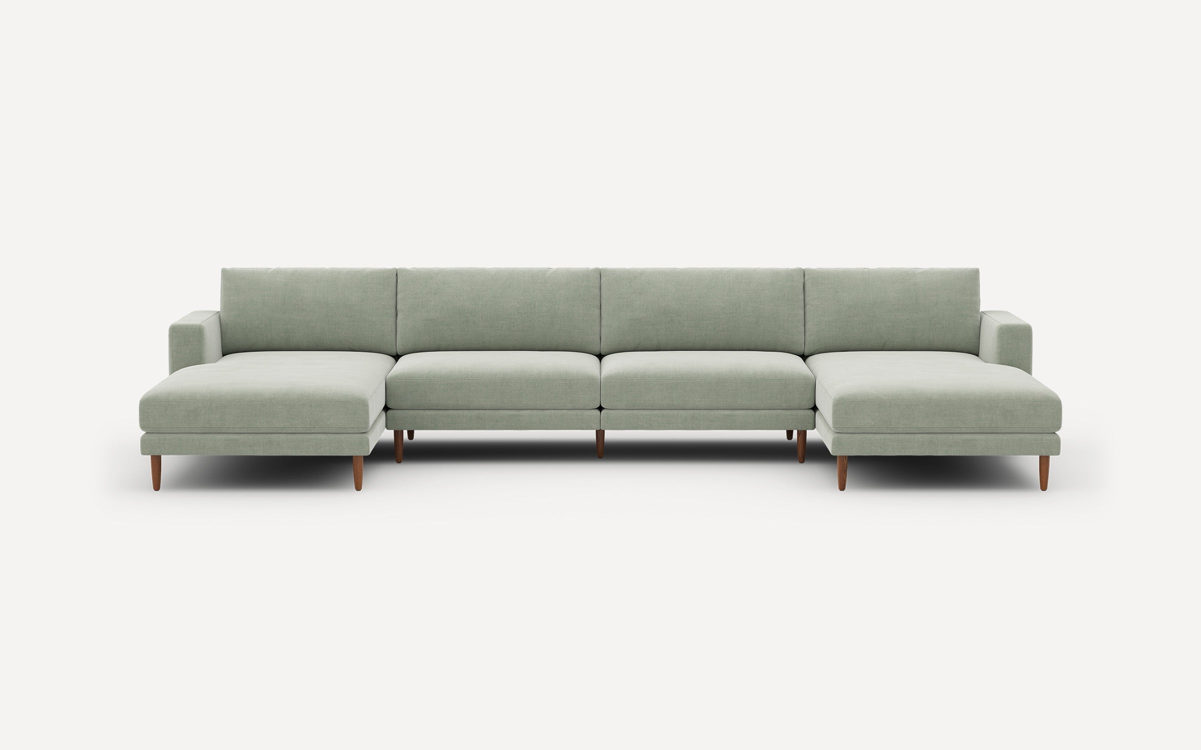 Light green modern sectional sofa with wooden legs, featuring two chaise lounges on each end and clean-lined cushions.