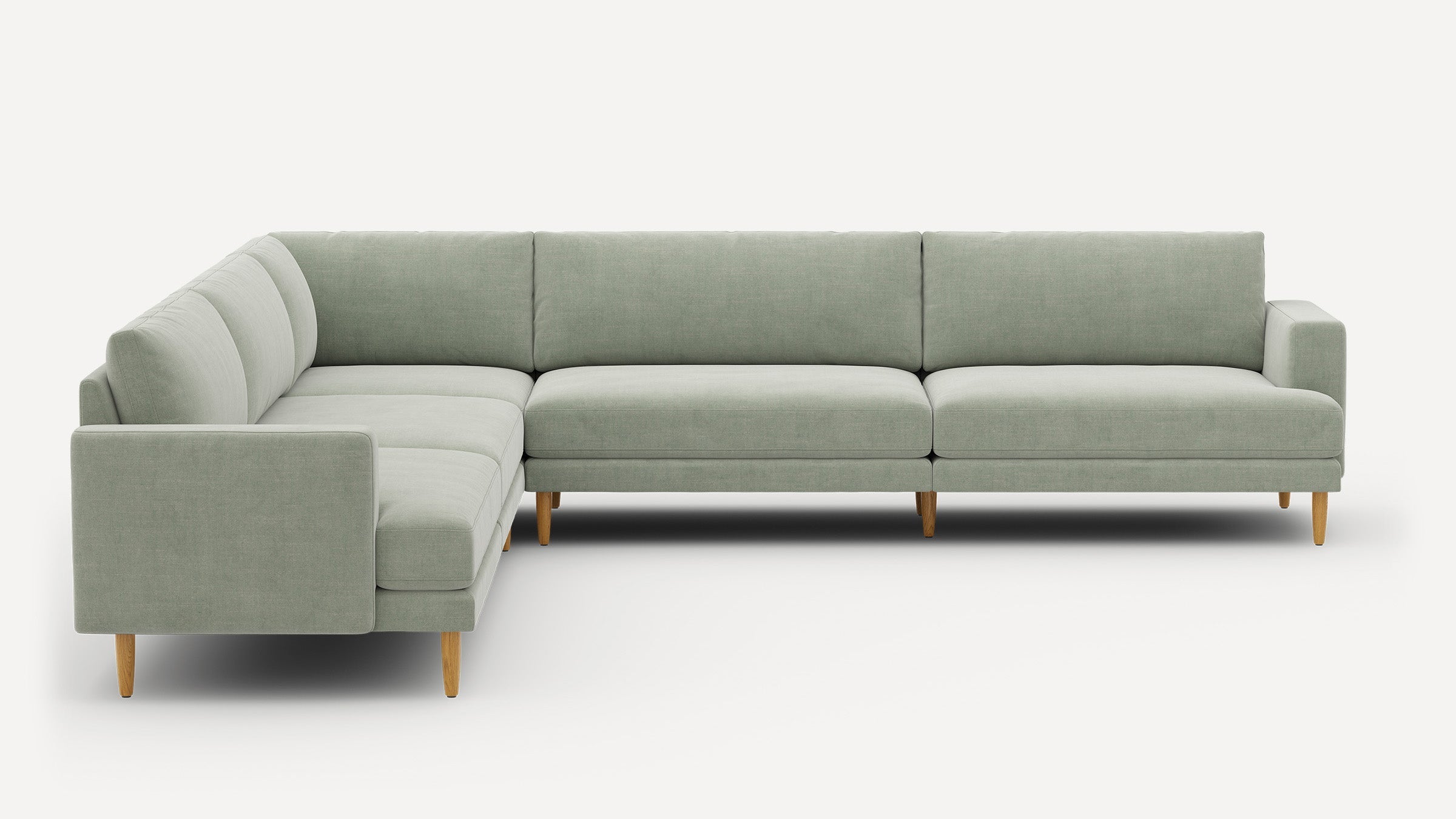 Light green L-shaped sectional sofa with wooden legs and clean, modern design against a white background.