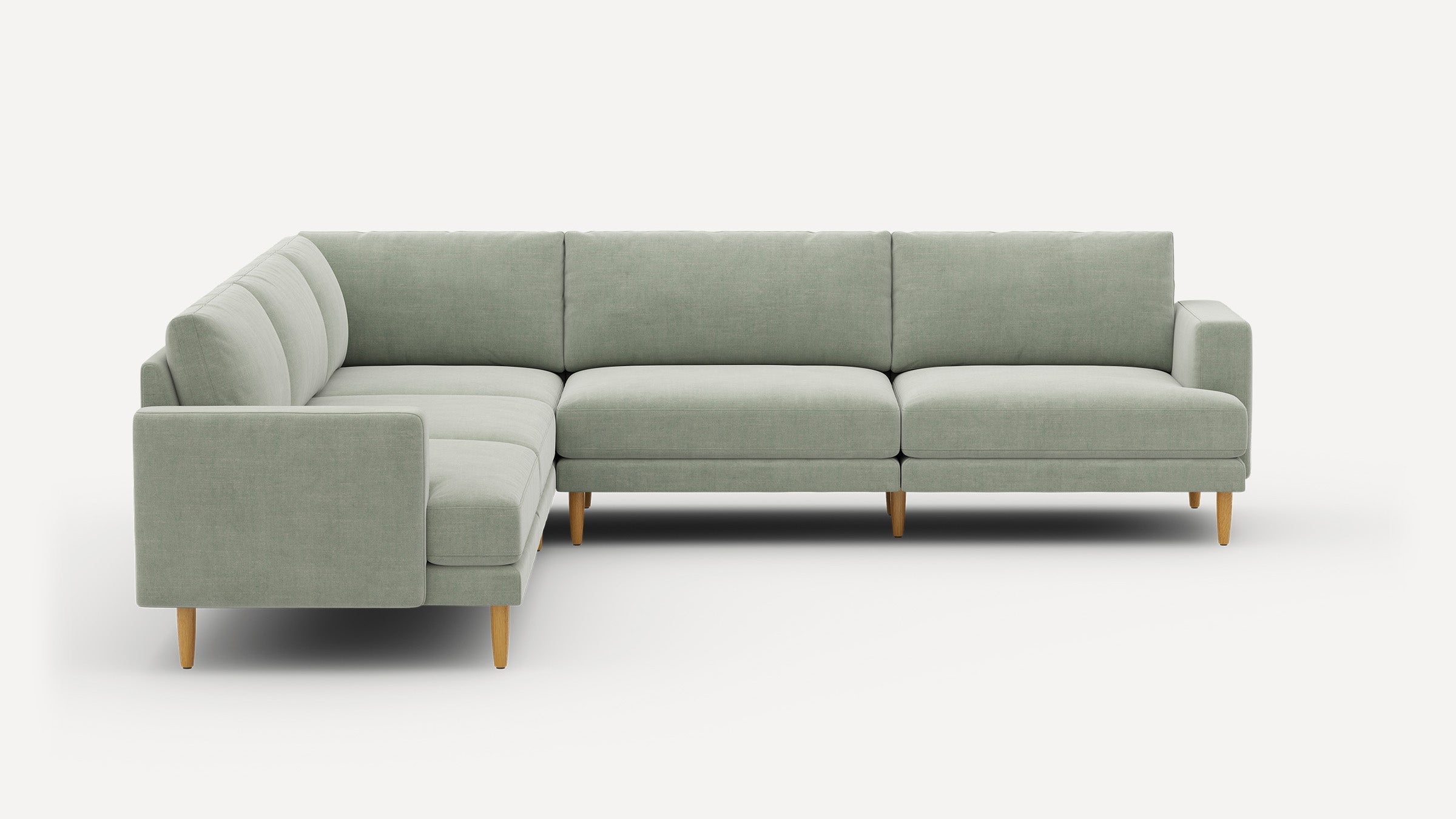 Light green L-shaped sectional sofa with wooden legs, clean lines, and contemporary minimalist design.
