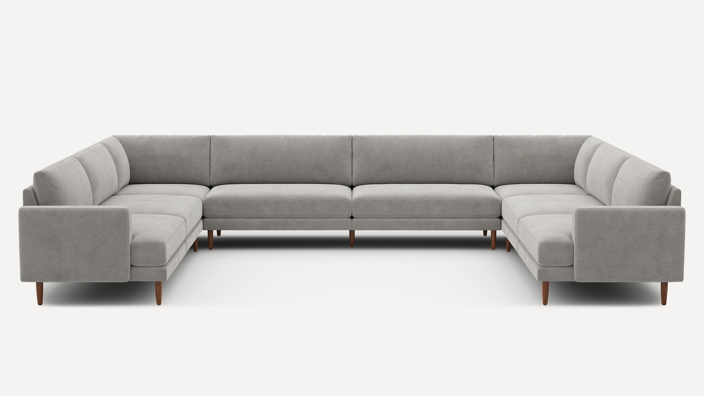 Large U-shaped sectional sofa in light gray fabric with clean lines and wooden tapered legs, modern minimalist design.