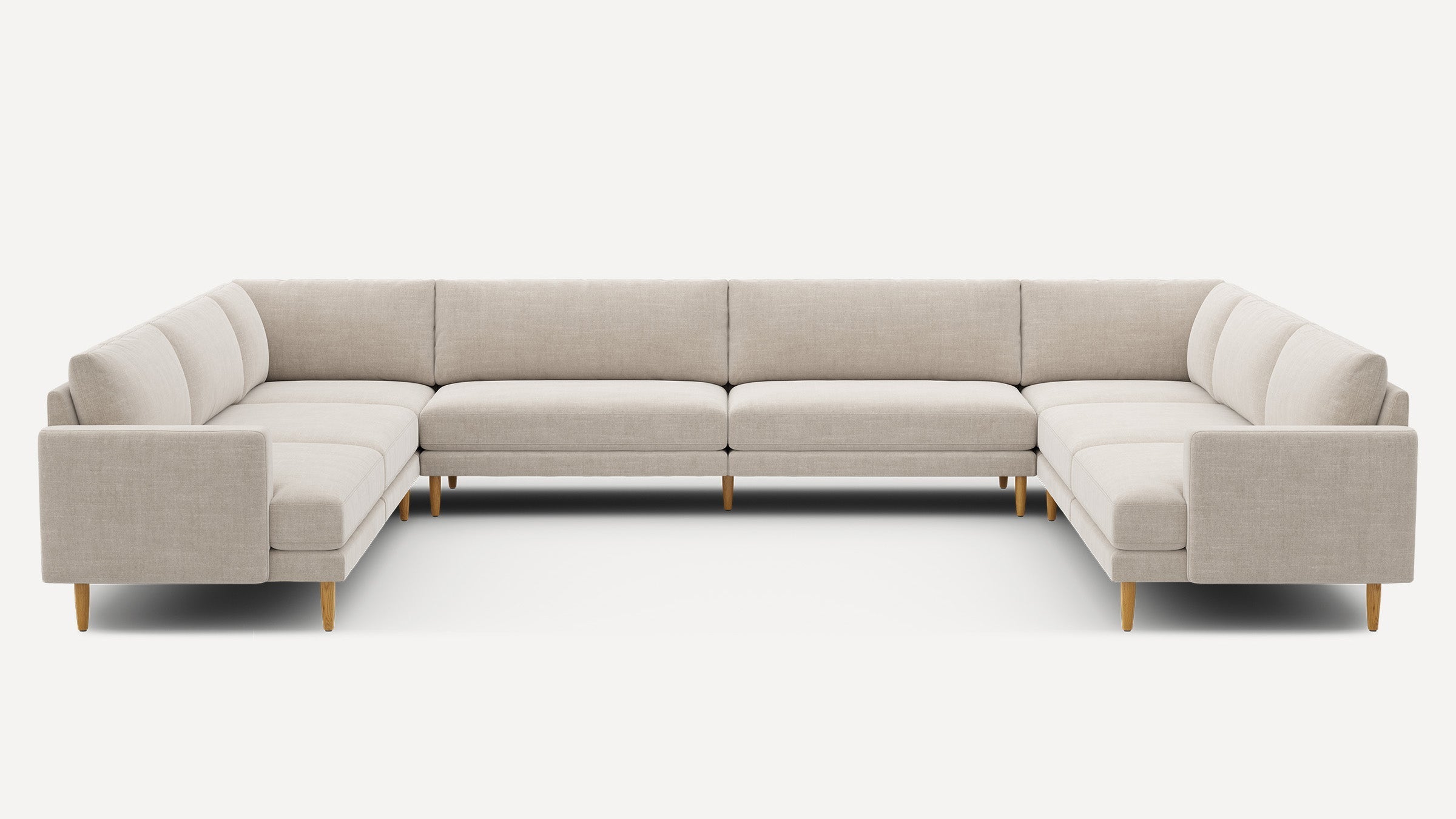 Large U-shaped beige sectional sofa with clean lines, fabric upholstery, and wooden legs, designed for modern living rooms.