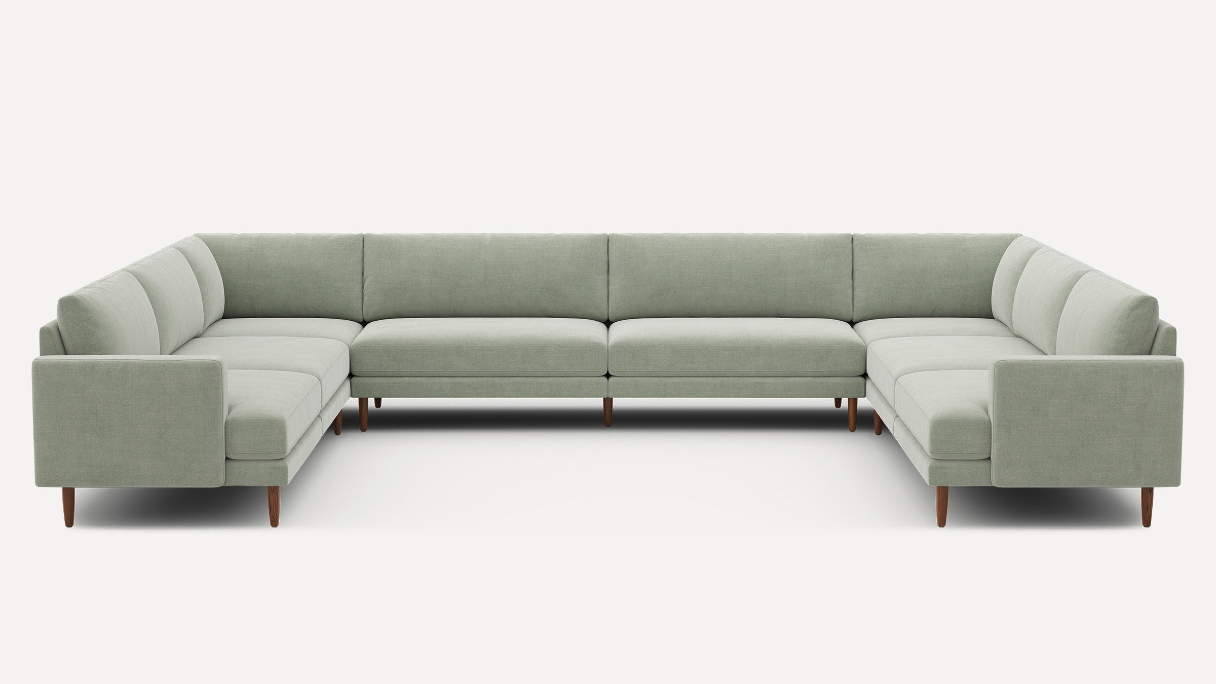 Large U-shaped sectional sofa with light green upholstery, clean lines, and wooden tapered legs for a modern aesthetic.