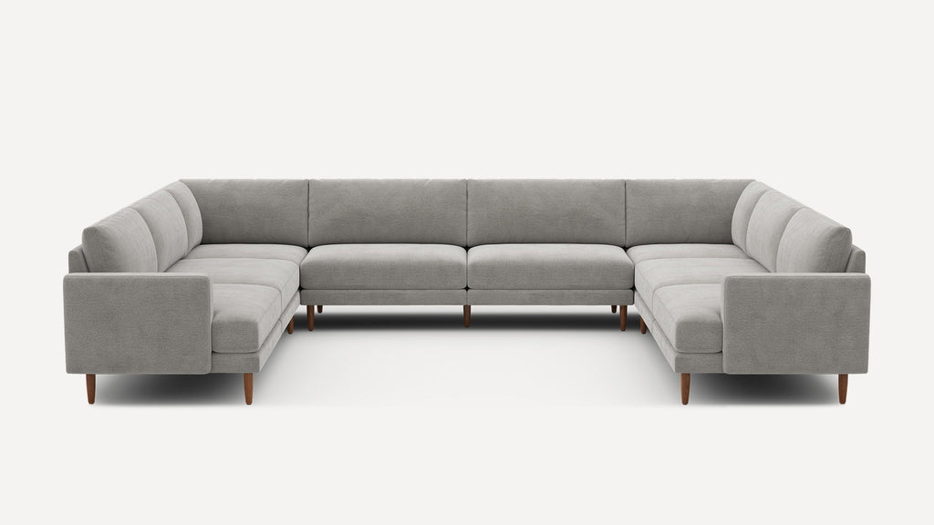Large gray fabric sectional sofa with wooden legs, modern design, and deep cushions, arranged in a U-shape.