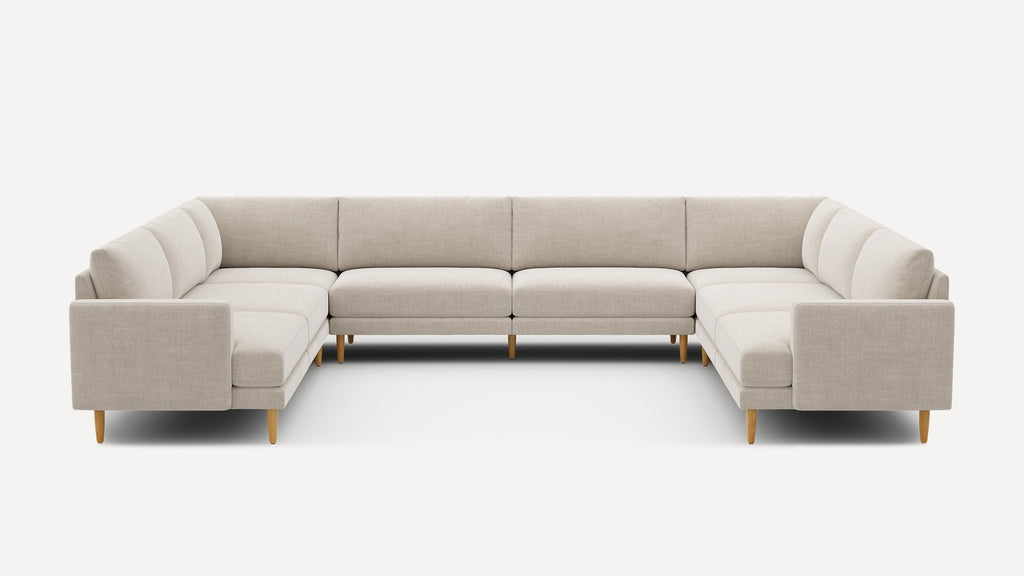 Large beige U-shaped sectional sofa with wooden legs, featuring clean lines and cushioned seating and backrests.