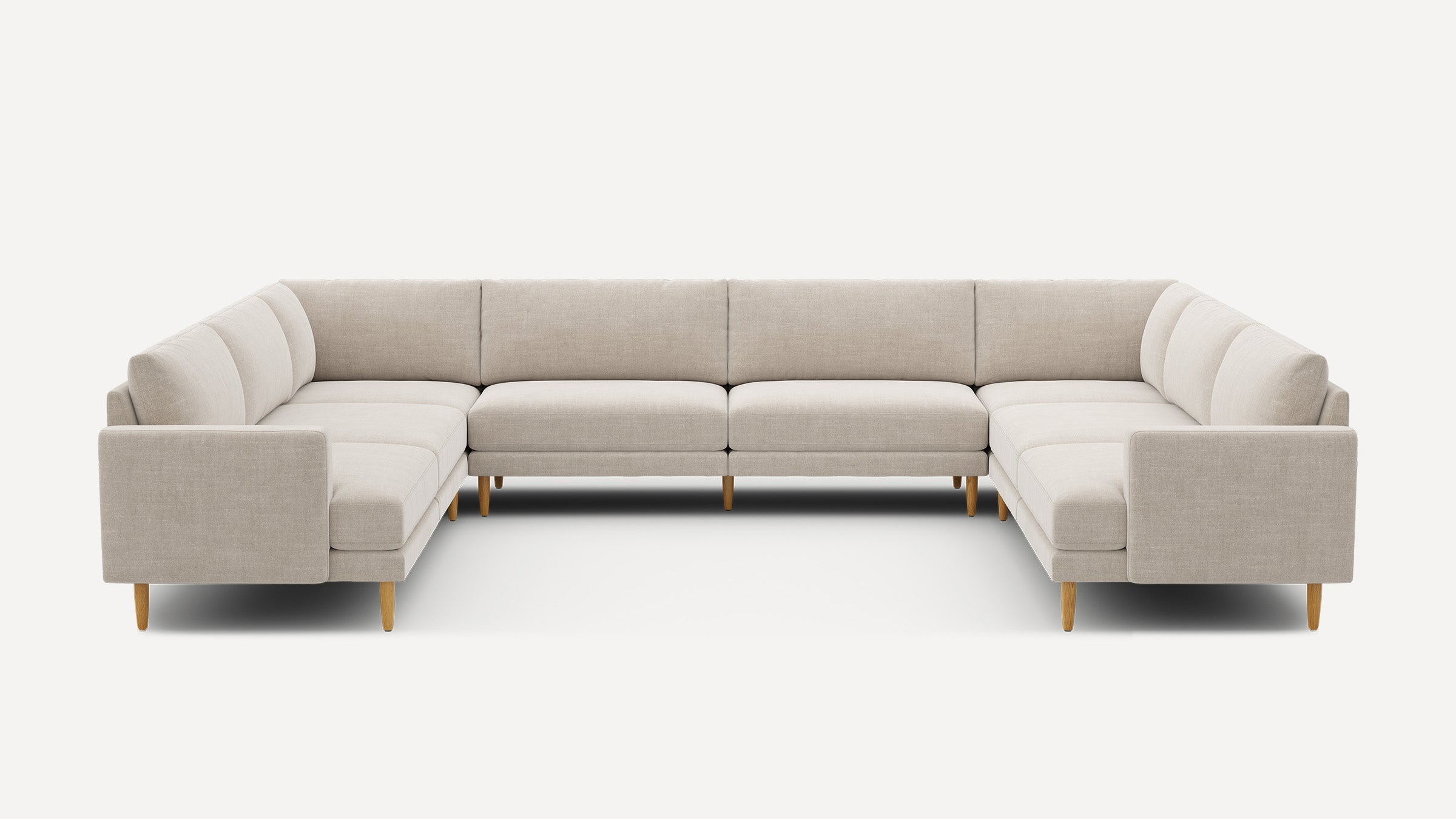 Large beige U-shaped sectional sofa with wooden legs, featuring clean lines and cushioned seating and backrests.