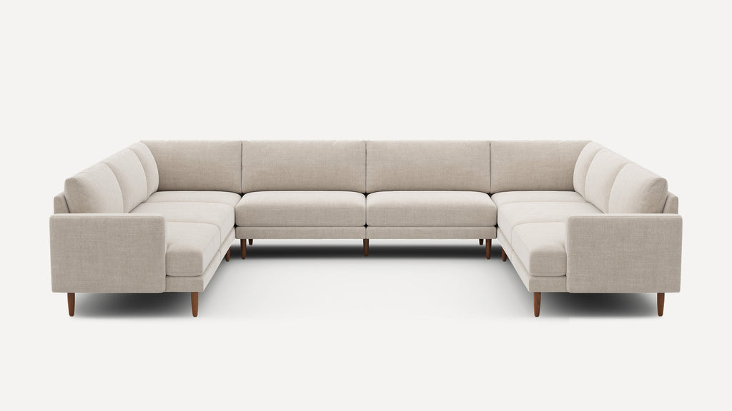 Large U-shaped beige fabric sectional sofa with wooden tapered legs, modern design, and cushioned seats and backrests.