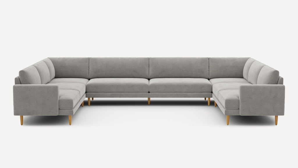 Large U-shaped sectional sofa with light gray upholstery and wooden legs, featuring clean modern lines and cushioned seating.
