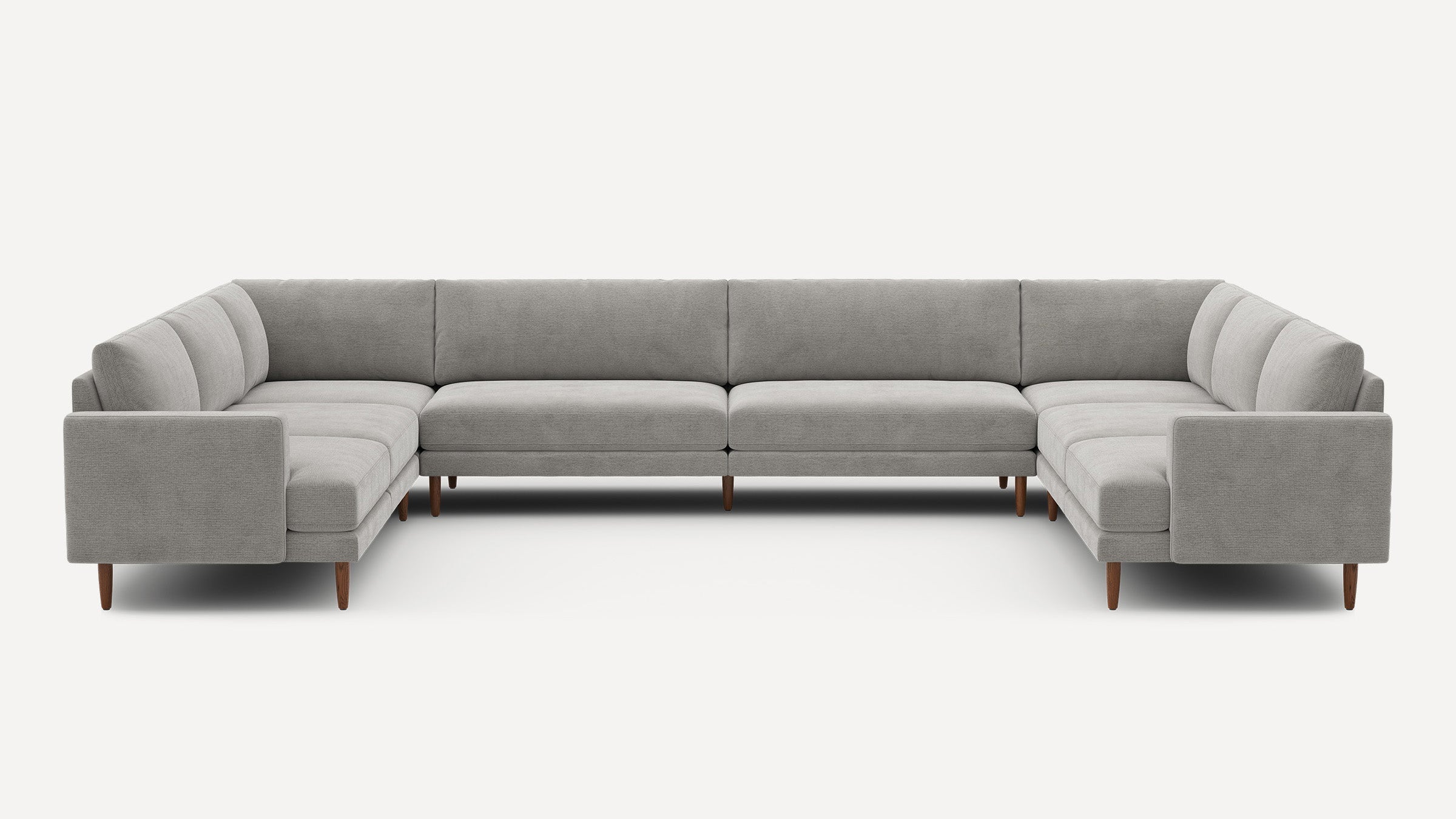 Large U-shaped sectional sofa upholstered in light gray fabric with tufted cushions and wooden tapered legs.