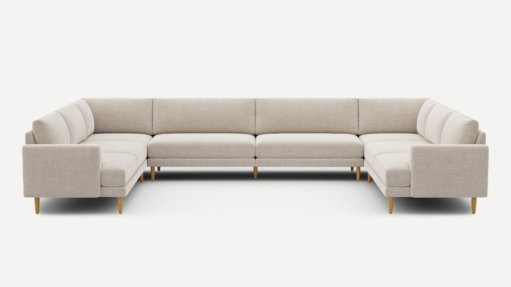 Large modern U-shaped sectional sofa with beige fabric upholstery and wooden legs, designed for spacious living areas.