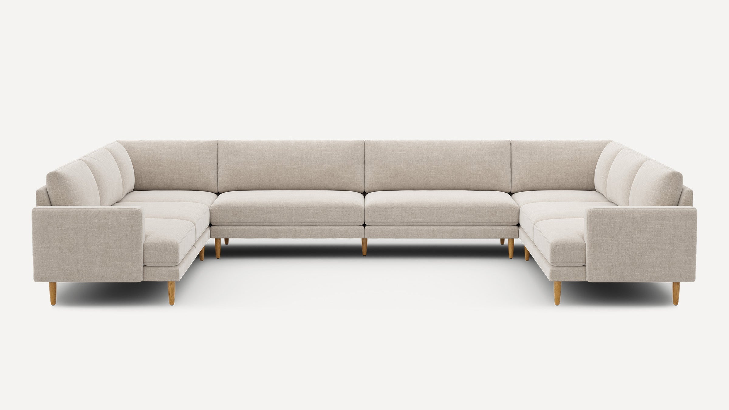 Large modern U-shaped sectional sofa with beige fabric upholstery and wooden legs, designed for spacious living areas.