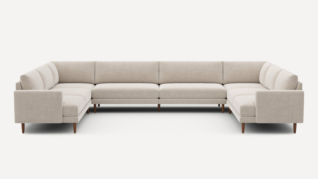 Large beige fabric U-shaped sectional sofa with straight arms and wooden tapered legs on a white background.