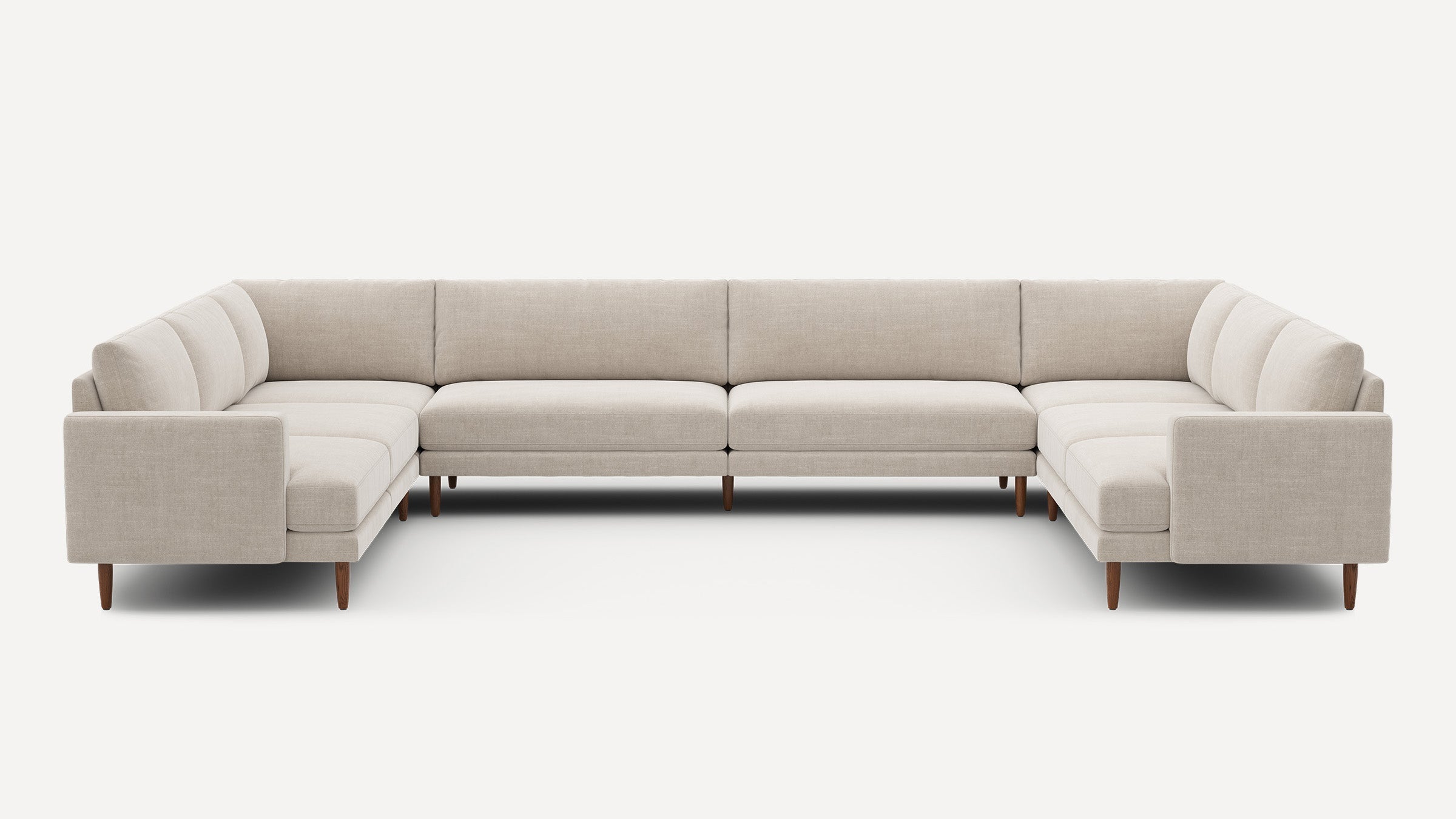 Large beige fabric U-shaped sectional sofa with straight arms and wooden tapered legs on a white background.