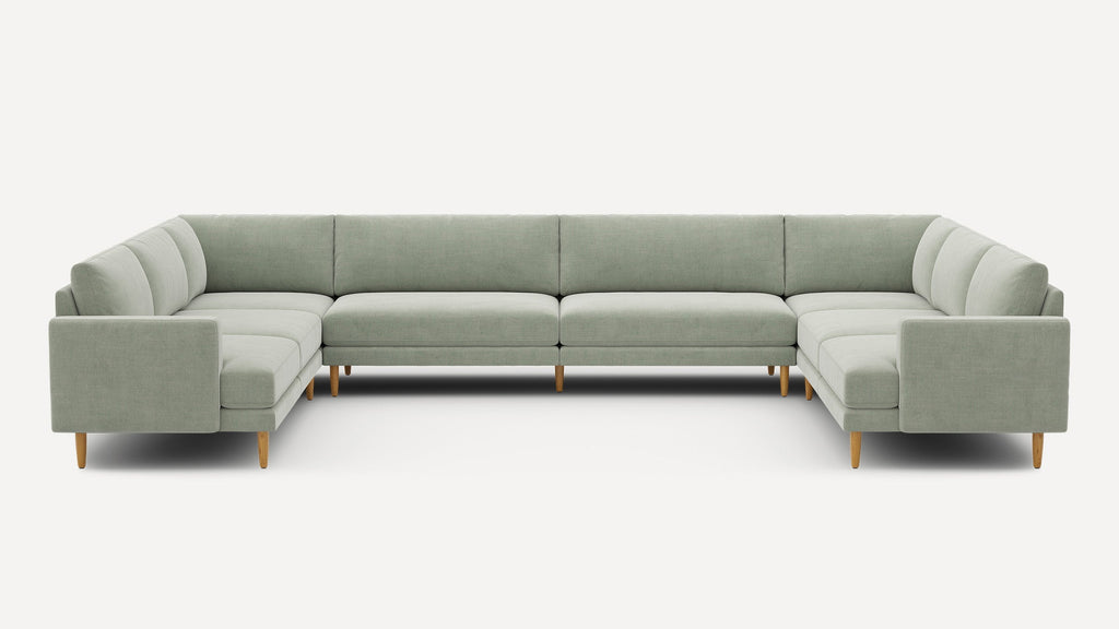 Large U-shaped sectional sofa upholstered in light sage green fabric with clean lines and wooden legs.