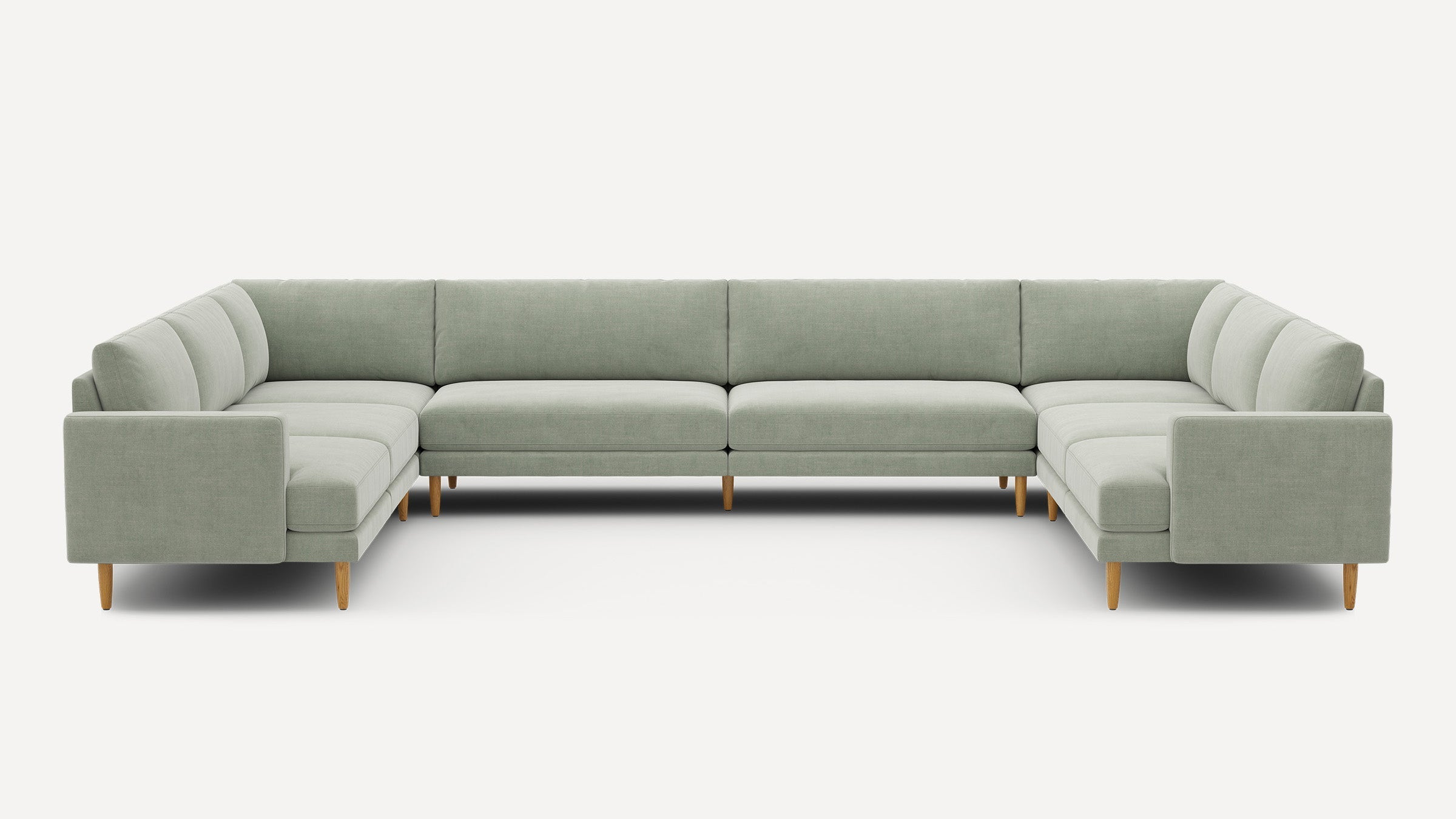 Large U-shaped sectional sofa upholstered in light sage green fabric with clean lines and wooden legs.