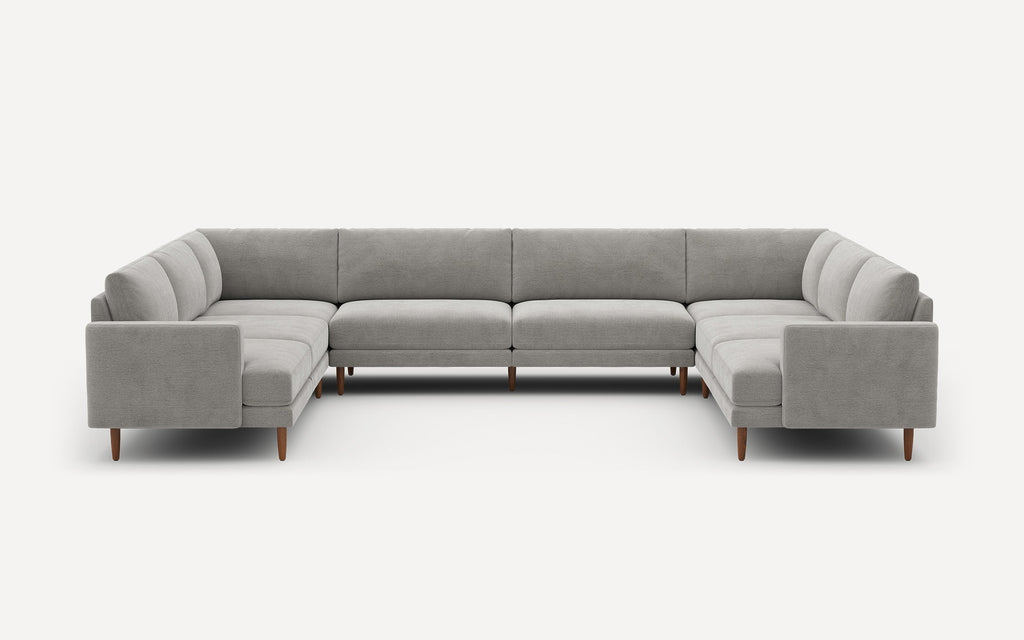 Large modern U-shaped sectional sofa in light gray fabric with wooden legs against a plain white background.