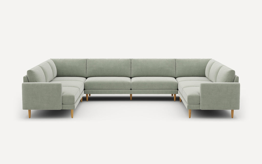 Large U-shaped sectional sofa in light gray fabric with wooden legs, featuring clean, modern lines and tufted cushions.