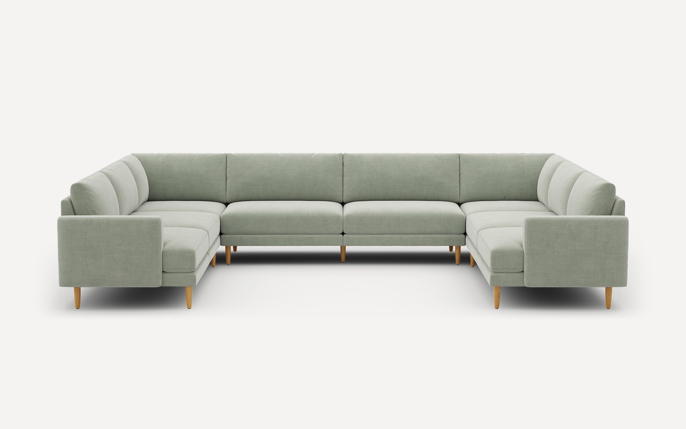 Large U-shaped sectional sofa in light gray fabric with wooden legs, featuring clean, modern lines and tufted cushions.