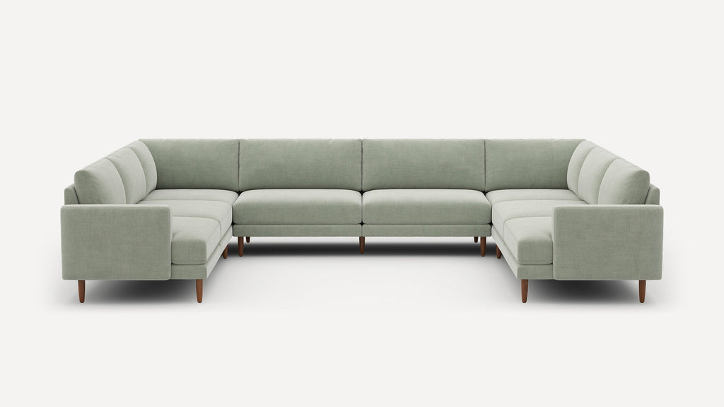 Large light gray-green U-shaped sectional sofa with clean lines, cushioned seats, and wooden legs on a plain white background.