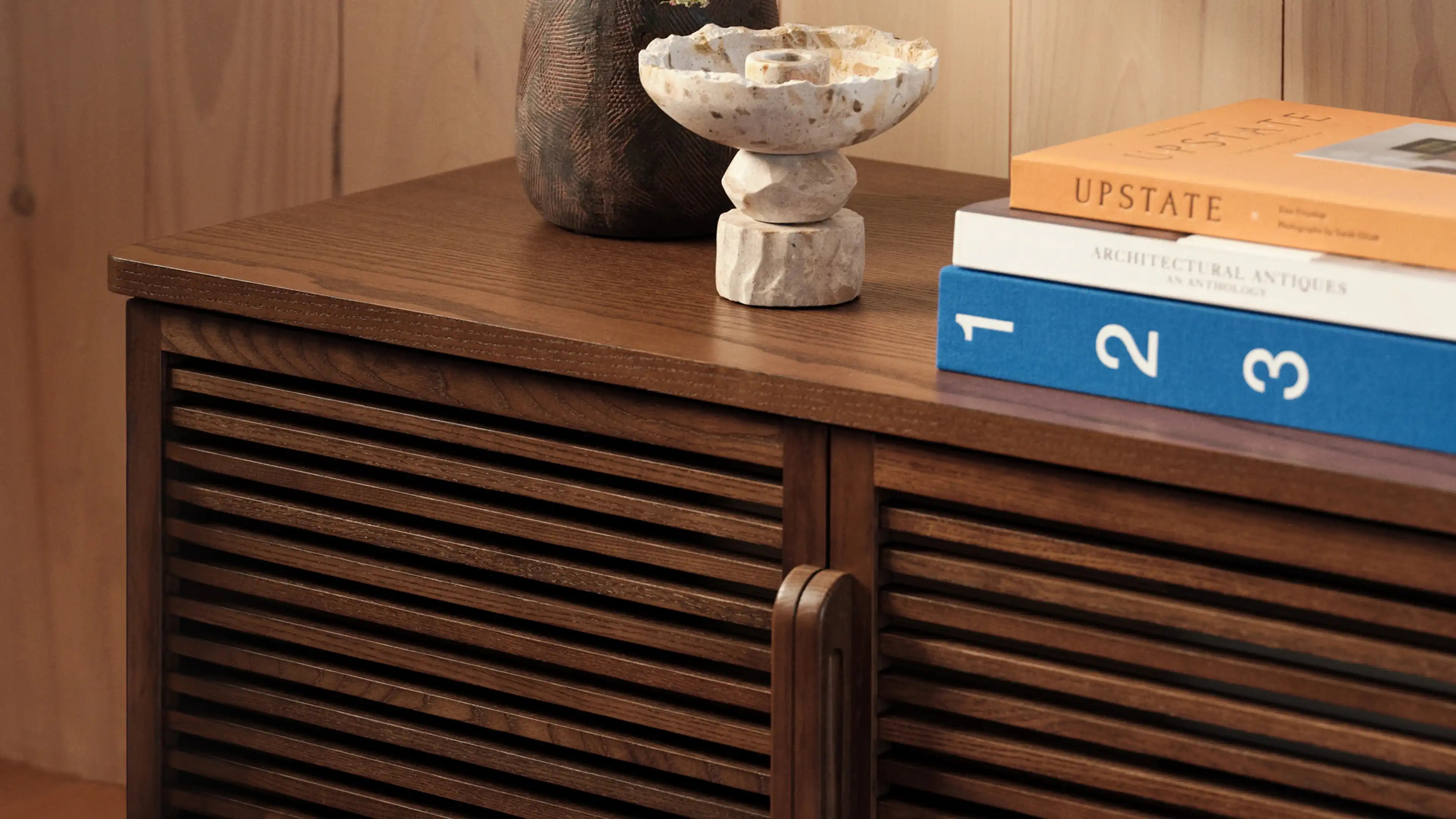 a wooden cabinet with a vase and a book on top