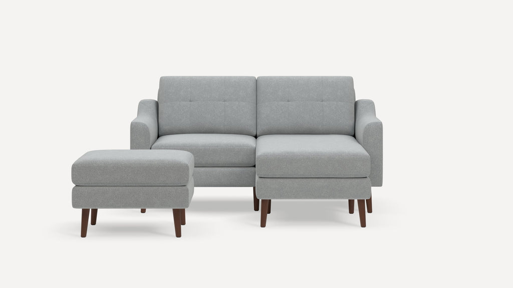 Light gray upholstered sectional sofa with wooden legs, including a right chaise lounge and a matching ottoman.