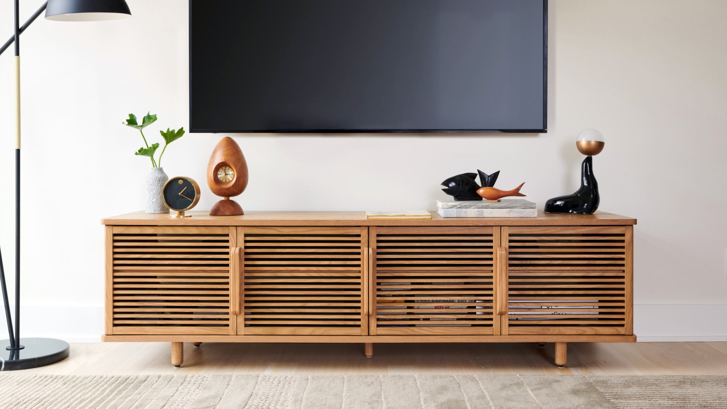 a tv stand with wooden slatted doors and a black screen mounted on the wall