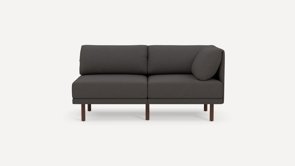 Dark gray modern two-seater sofa with wooden legs and an angled side cushion on a white background.