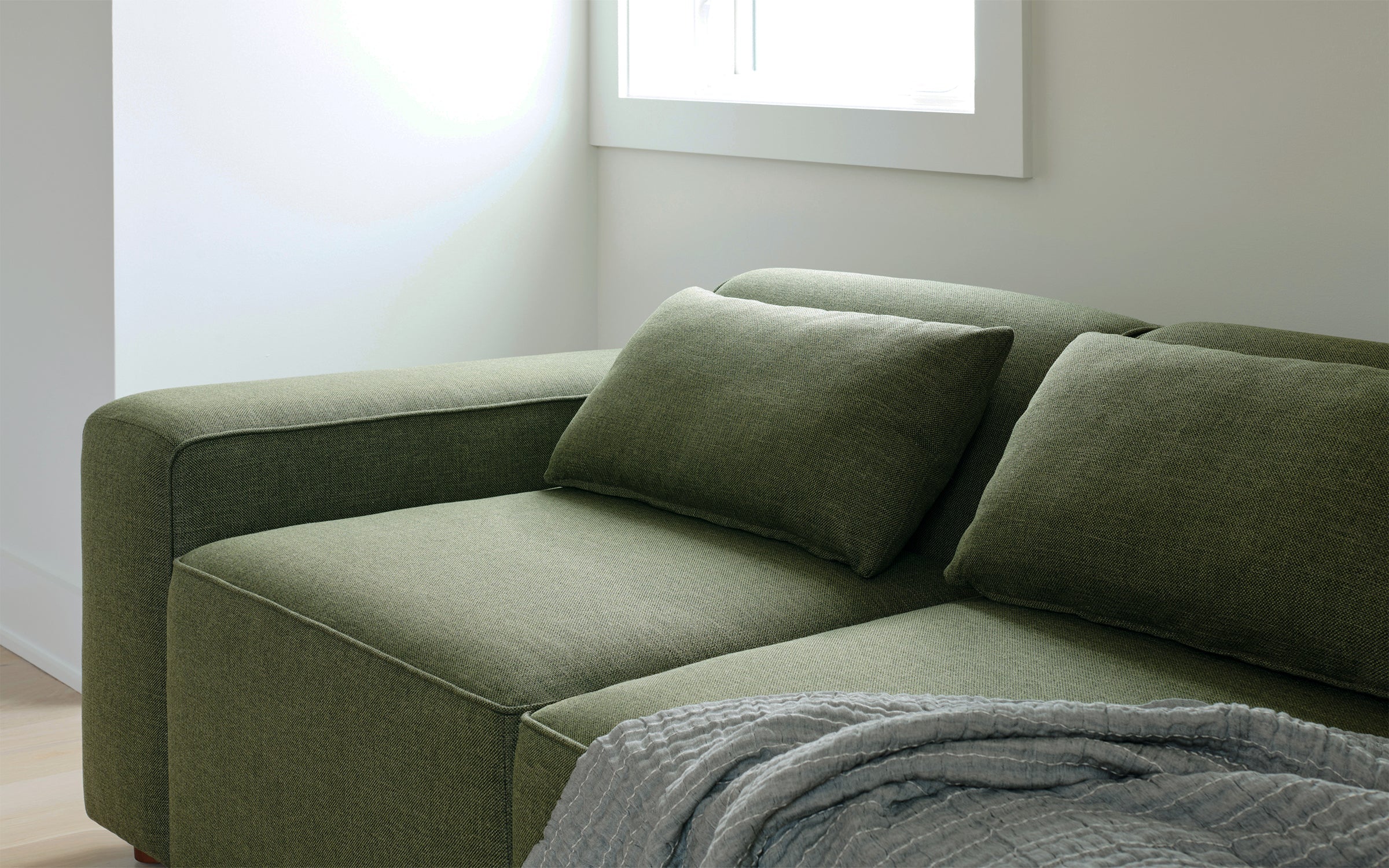 a green couch with pillows and a blanket on it