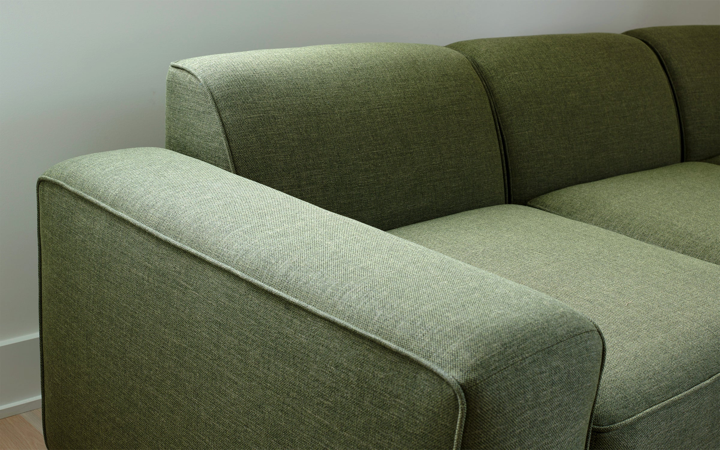 a green couch with a wooden floor and white walls