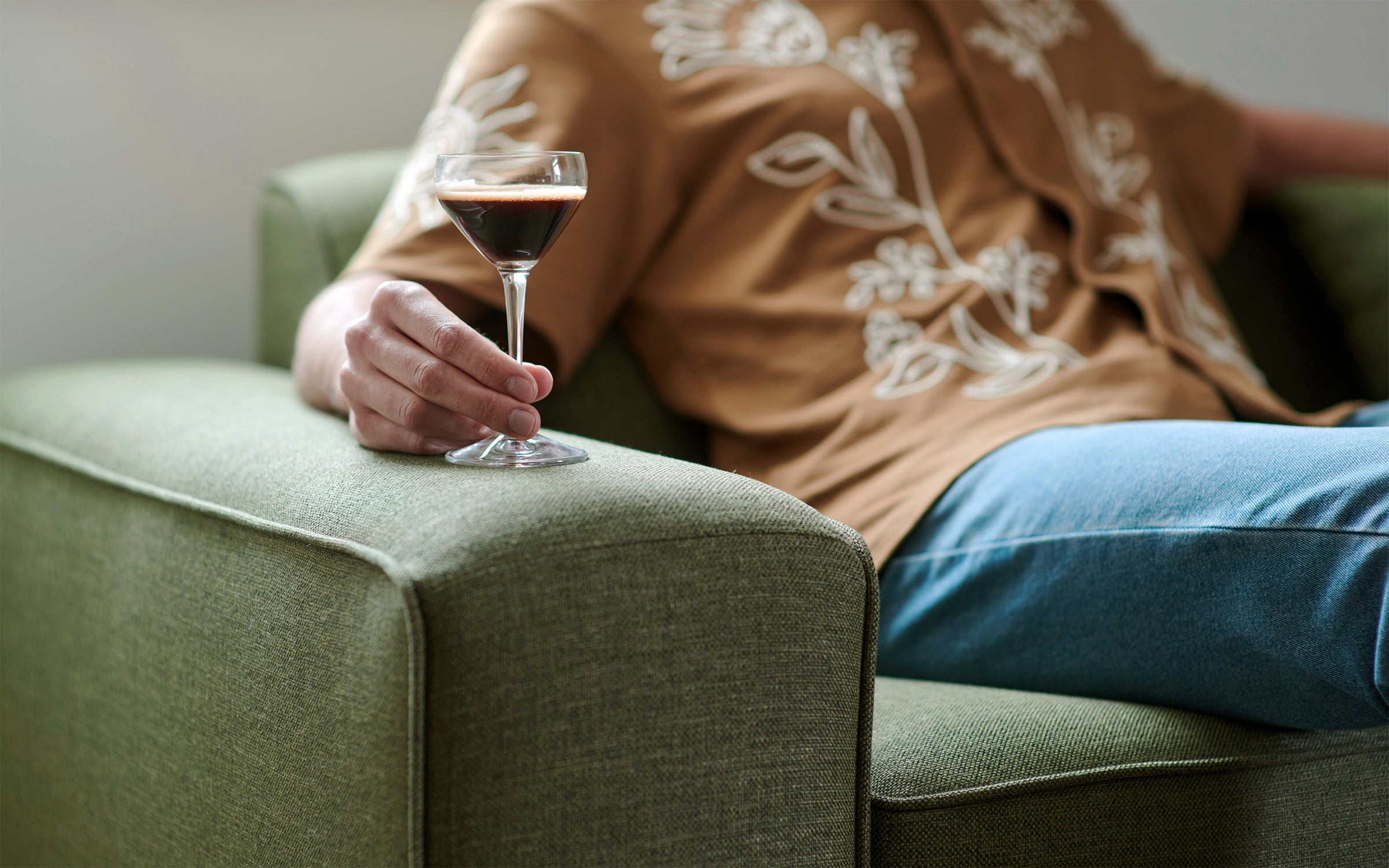 a man sitting on a couch holding a glass of wine