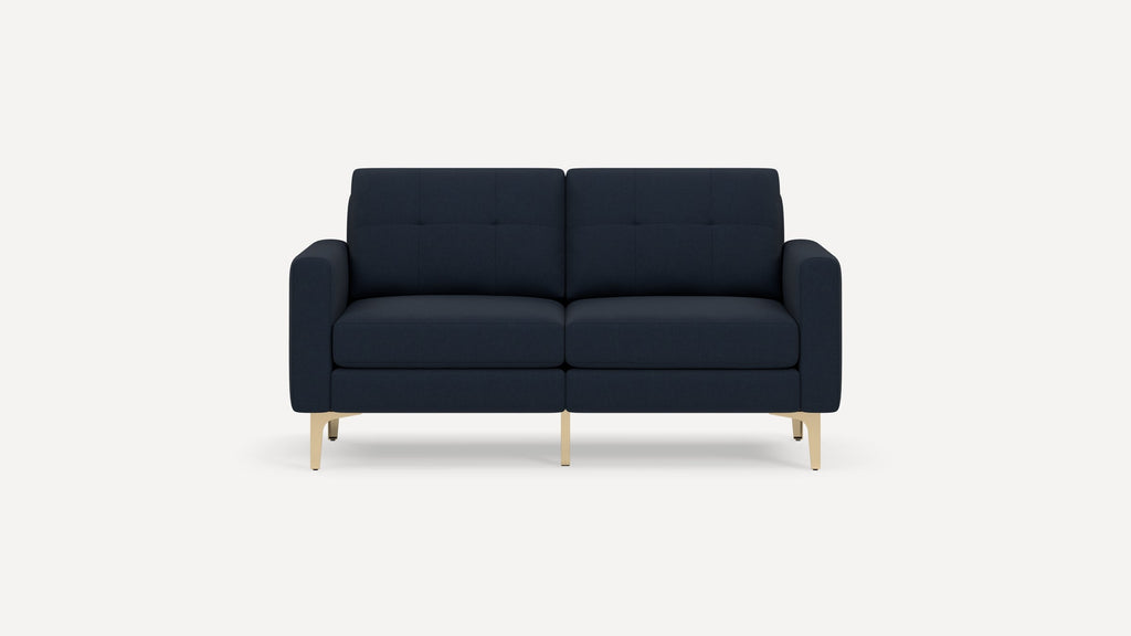 Modern navy blue two-seater sofa with tufted back cushions and sleek light wood legs on a white background.