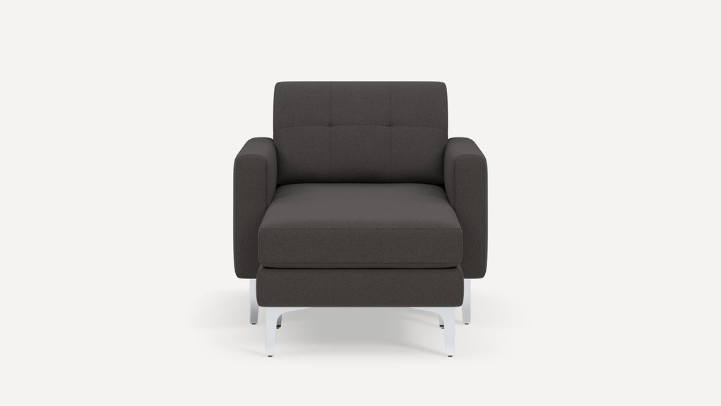 Front view of a dark gray modern armchair with tufted backrest and silver metal legs on a white background.