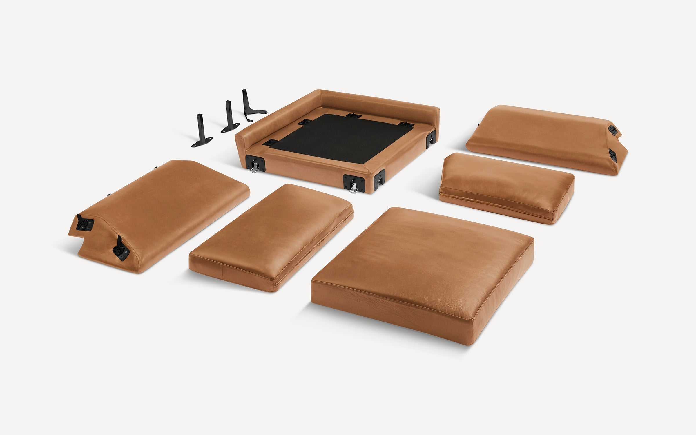 Flat lay of disassembled modern brown leather sofa cushions and frame components on a white background, showing upholstery details.