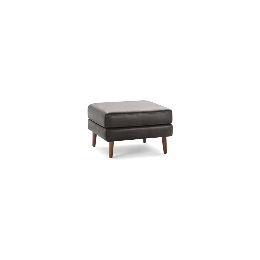 Square dark gray leather ottoman with tufted cushion top and four tapered wooden legs.