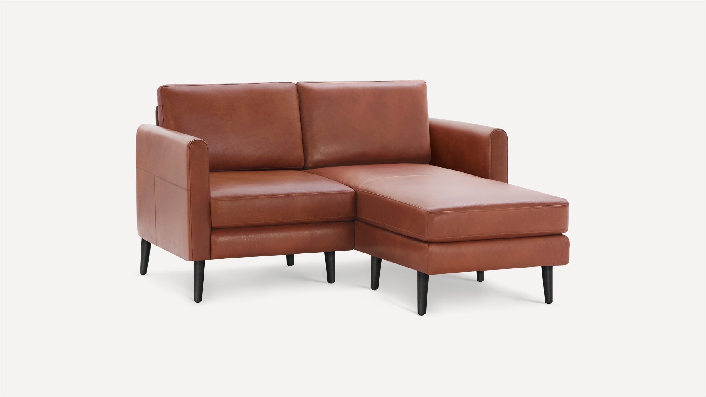 Modern brown leather sectional sofa with chaise lounge on right side and black tapered wooden legs.