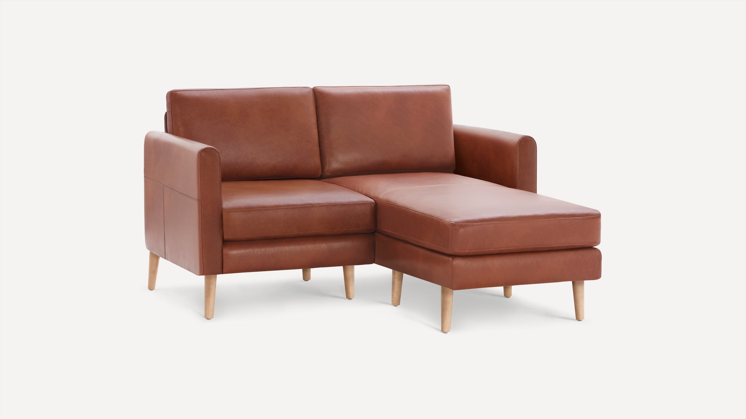 Modern brown leather sectional sofa with wooden legs and a chaise lounge on the right side, set against a plain white background.