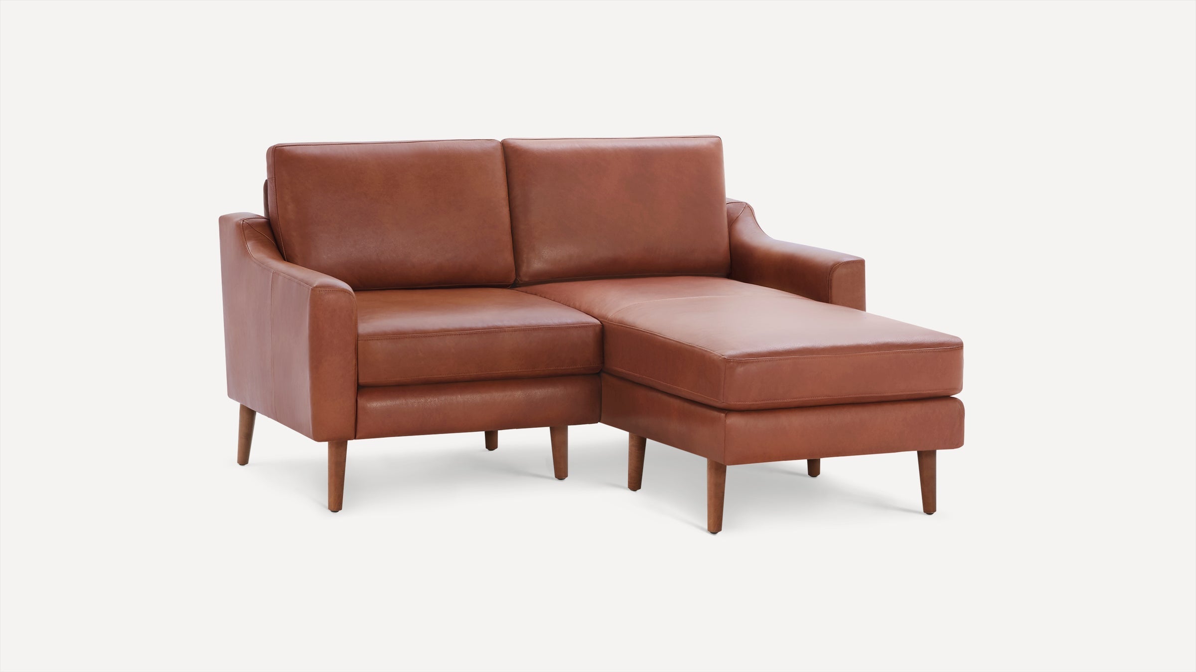 Mid-century modern brown leather sectional sofa with wooden legs and a chaise lounge on the right side, isolated on white background.