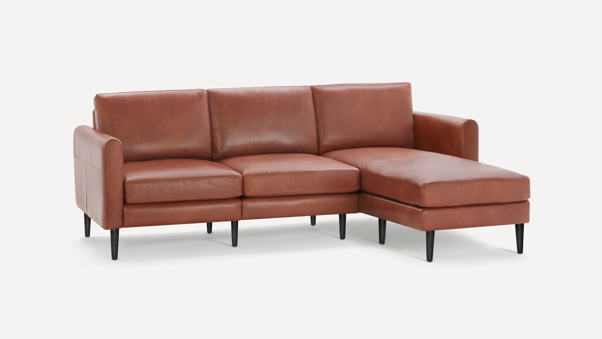 Brown leather sectional sofa with three seat cushions, a chaise on the right, cushioned backrests, and black tapered legs.