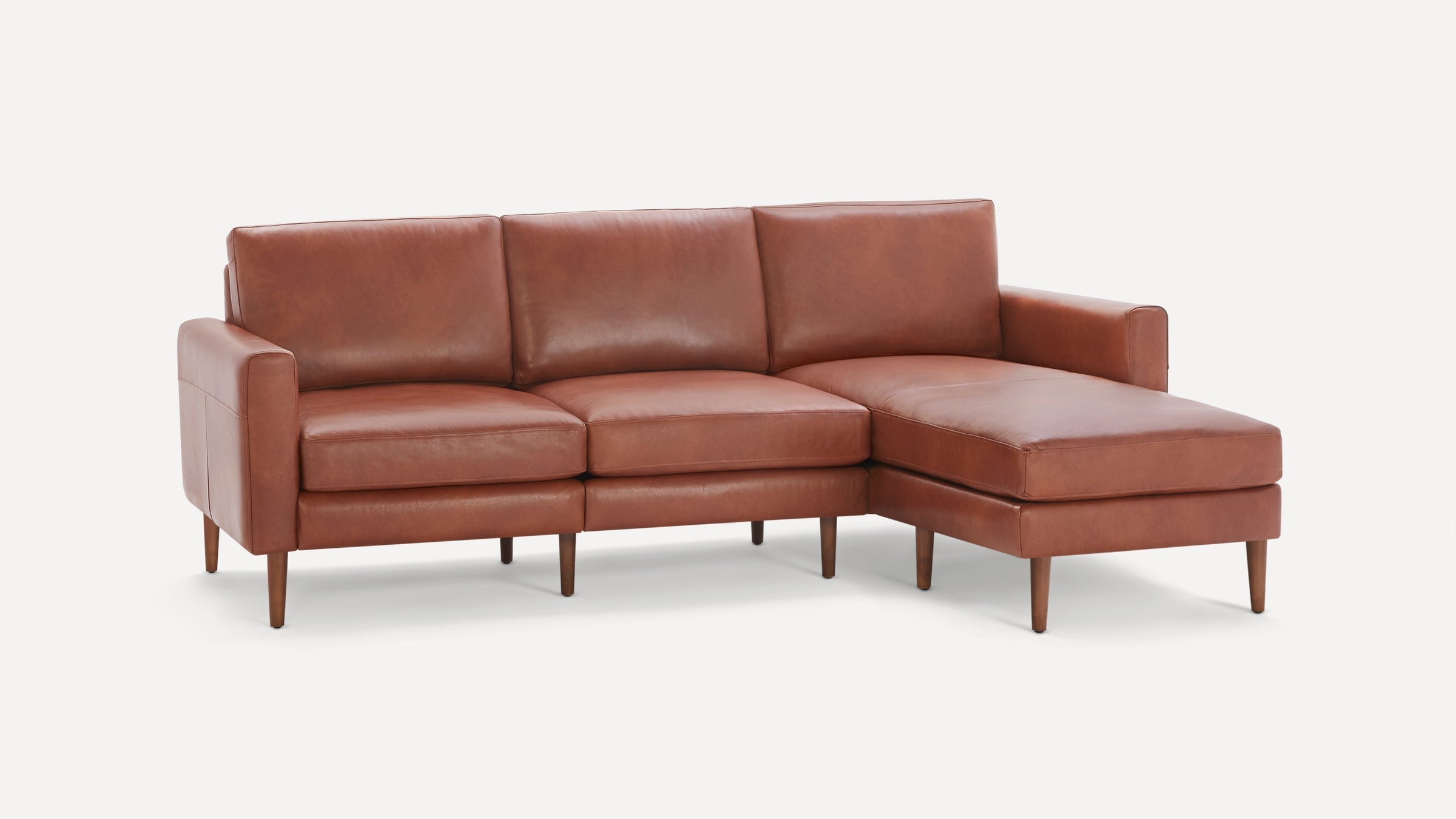 Modern brown leather sectional sofa with chaise lounge, clean lines, cushioned seats and wooden legs on white background.