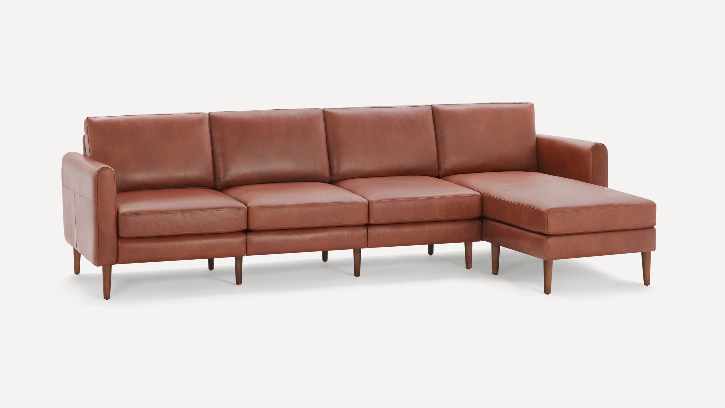 Modern brown leather sectional sofa with chaise lounge, smooth cushions, and wooden legs, set against a white background.