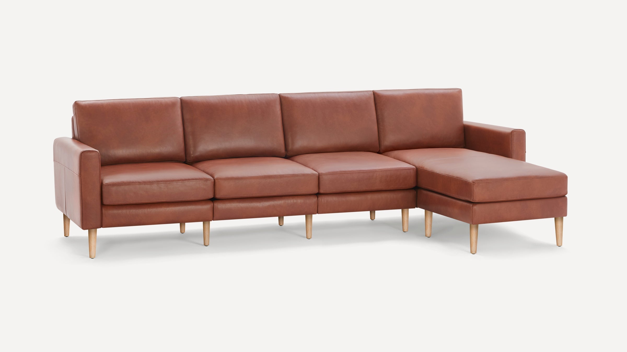 Modern brown leather sectional sofa with wooden legs, featuring three seats and a chaise lounge on the right side.