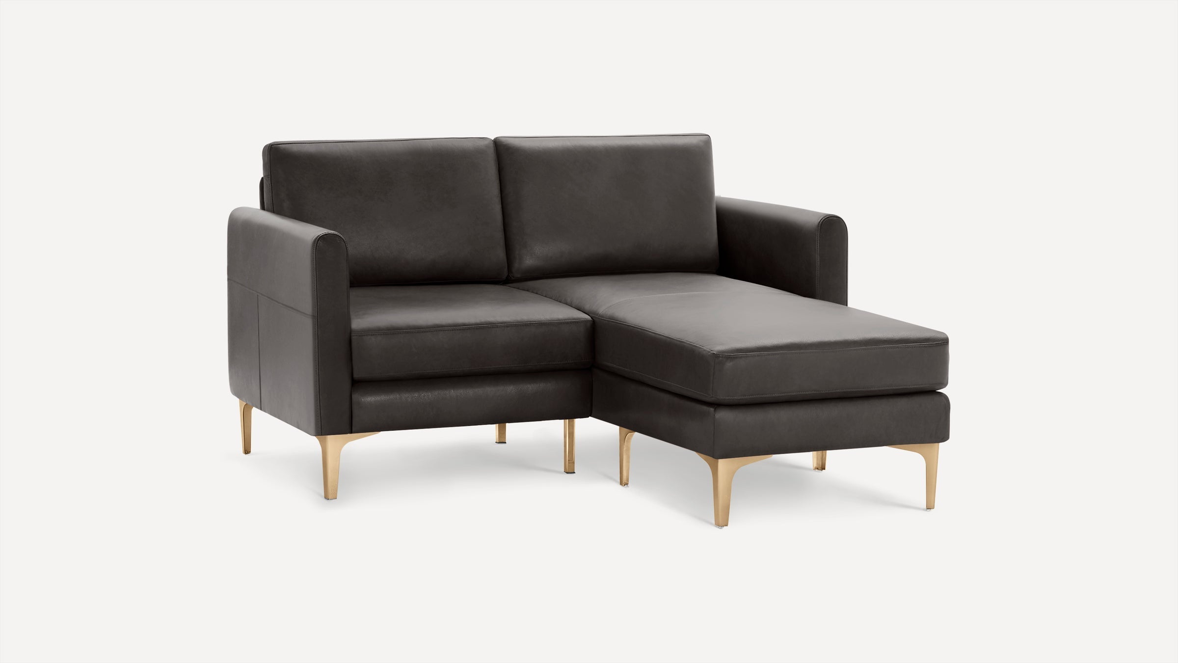Modern dark gray leather sectional sofa with chaise on the right and gold-toned metal legs, minimalist design.
