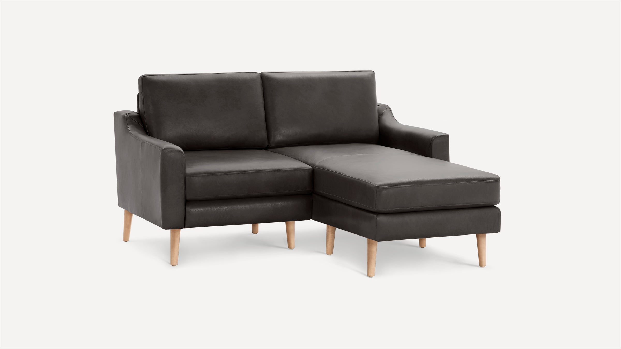 Dark gray modern sectional sofa with chaise lounge on right side and light wood legs, set against a plain white background.