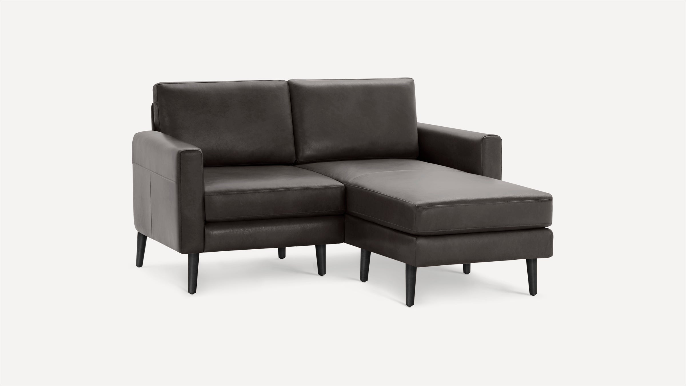Dark gray upholstered sectional sofa with chaise lounge, straight arms, and tapered black legs on a white background.