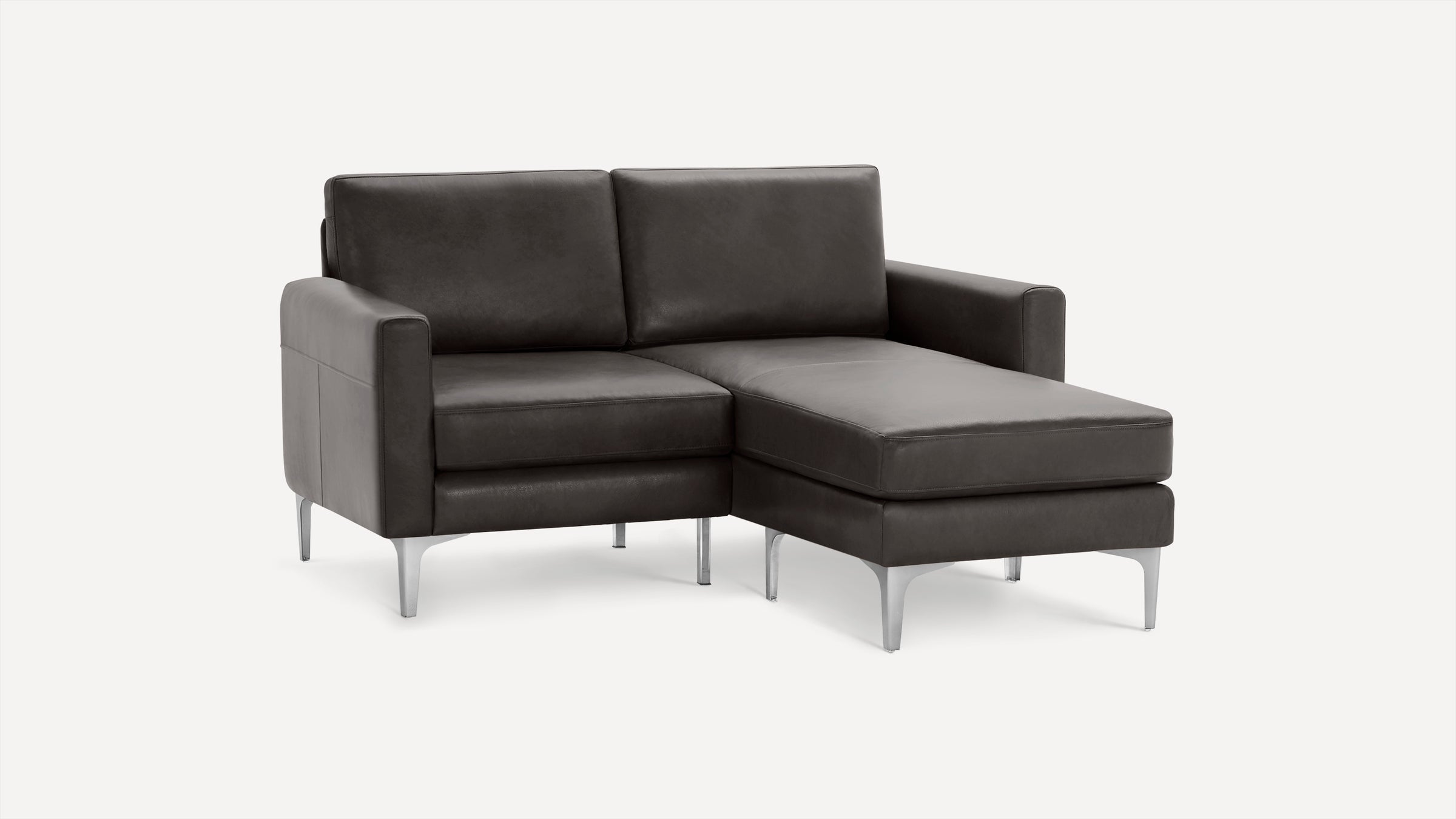 Modern dark gray leather sectional sofa with metal legs and a chaise lounge on the right side, set against a plain white background.